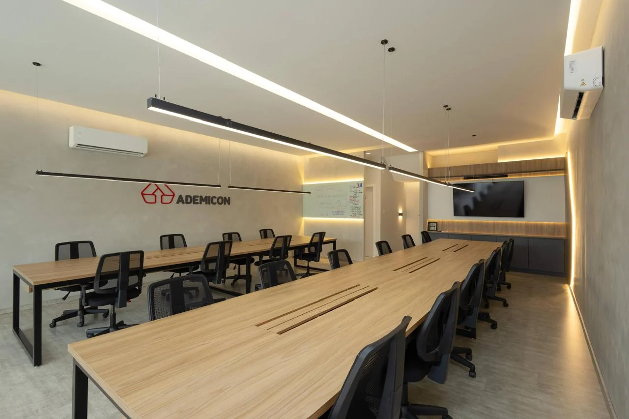 Sala de reunião Ademicon com mesas planejadas e iluminação linear suspensa